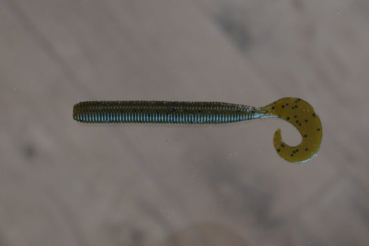 A soft plastic fishing lure shaped like a segmented worm with a curved tail, shown on a light gray surface.